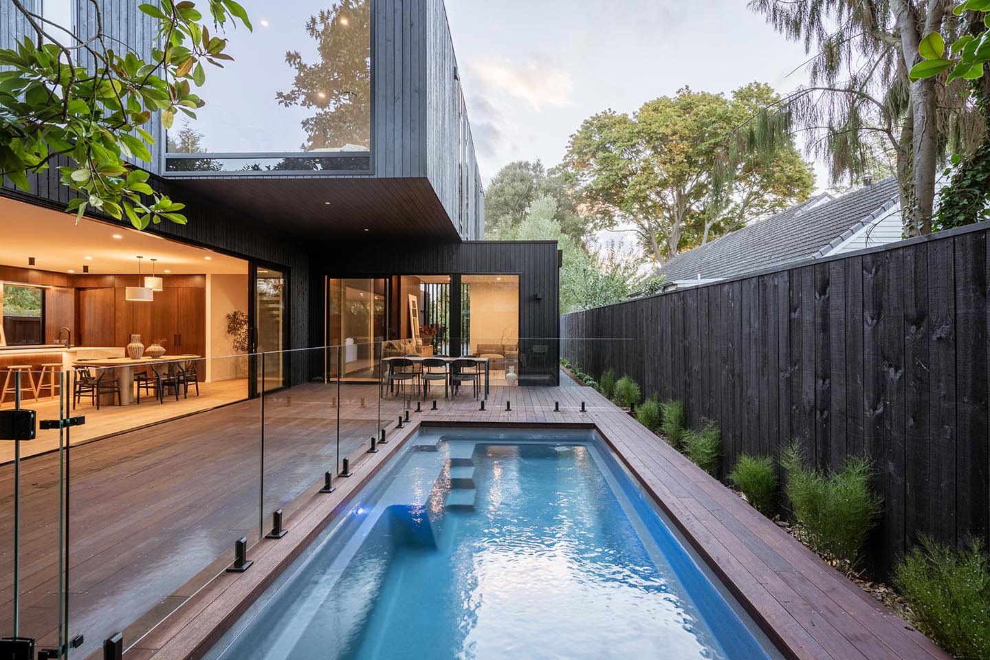 Bryndwr I pool courtyard with full-height glazing, dark timber cladding and a cantilevered upper level projecting above the deck.