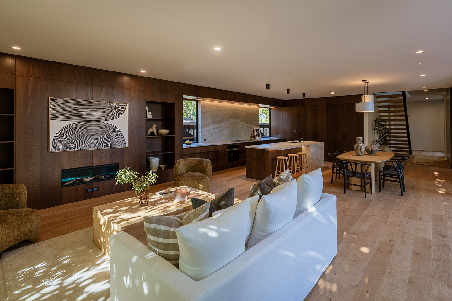 Bryndwr I open-plan living, dining and kitchen area with timber cabinetry, pale flooring and a long island beneath pendant lights.