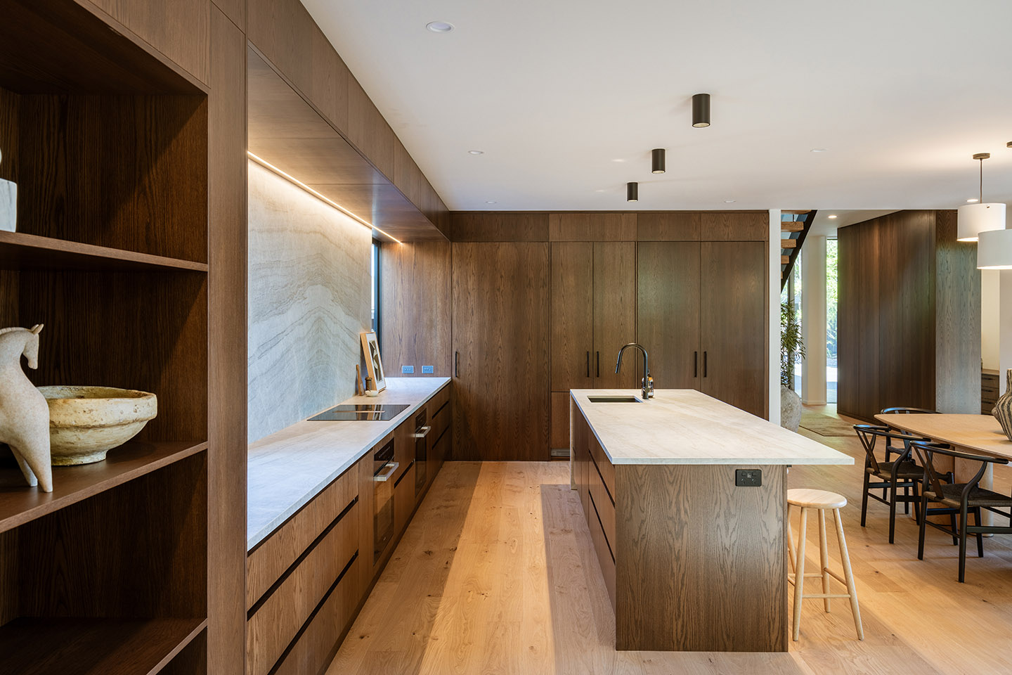 Bryndwr I kitchen with timber cabinetry, pale stone benchtops and a long island beside the open dining area.