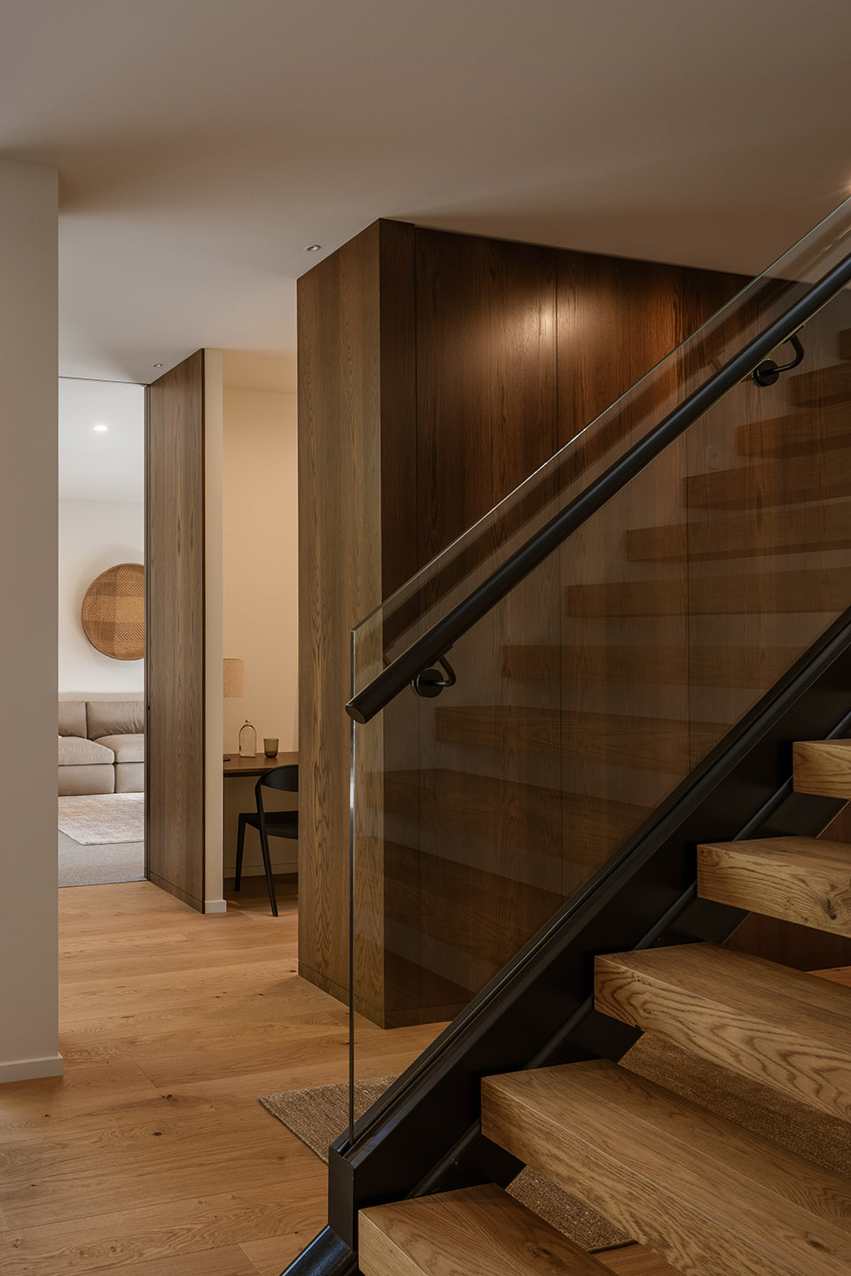 Bryndwr I timber stair with open treads, dark steel structure and glass balustrade beside a compact study nook.