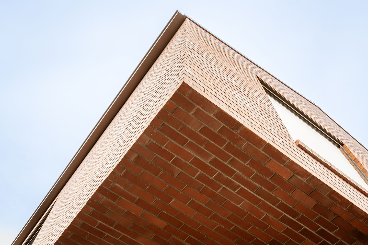 Low-angle detail of Bryndwr II showing the brick-clad upper level and deep cantilevered brick soffit.