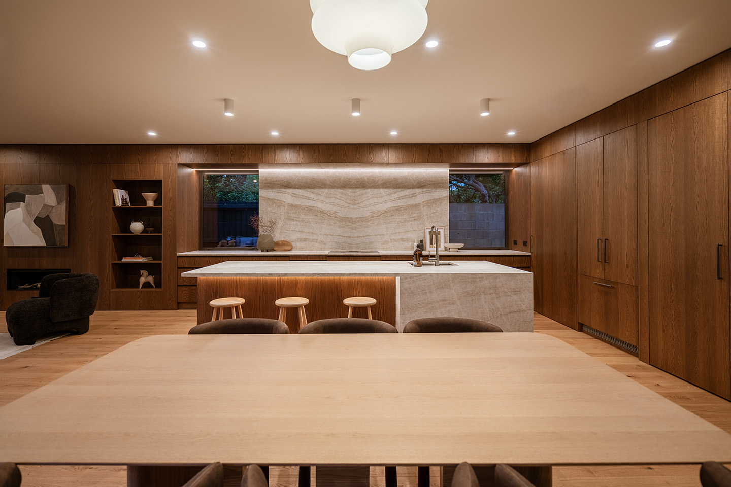 Bryndwr II kitchen with dark timber cabinetry, pale stone surfaces and a large island facing the dining area.