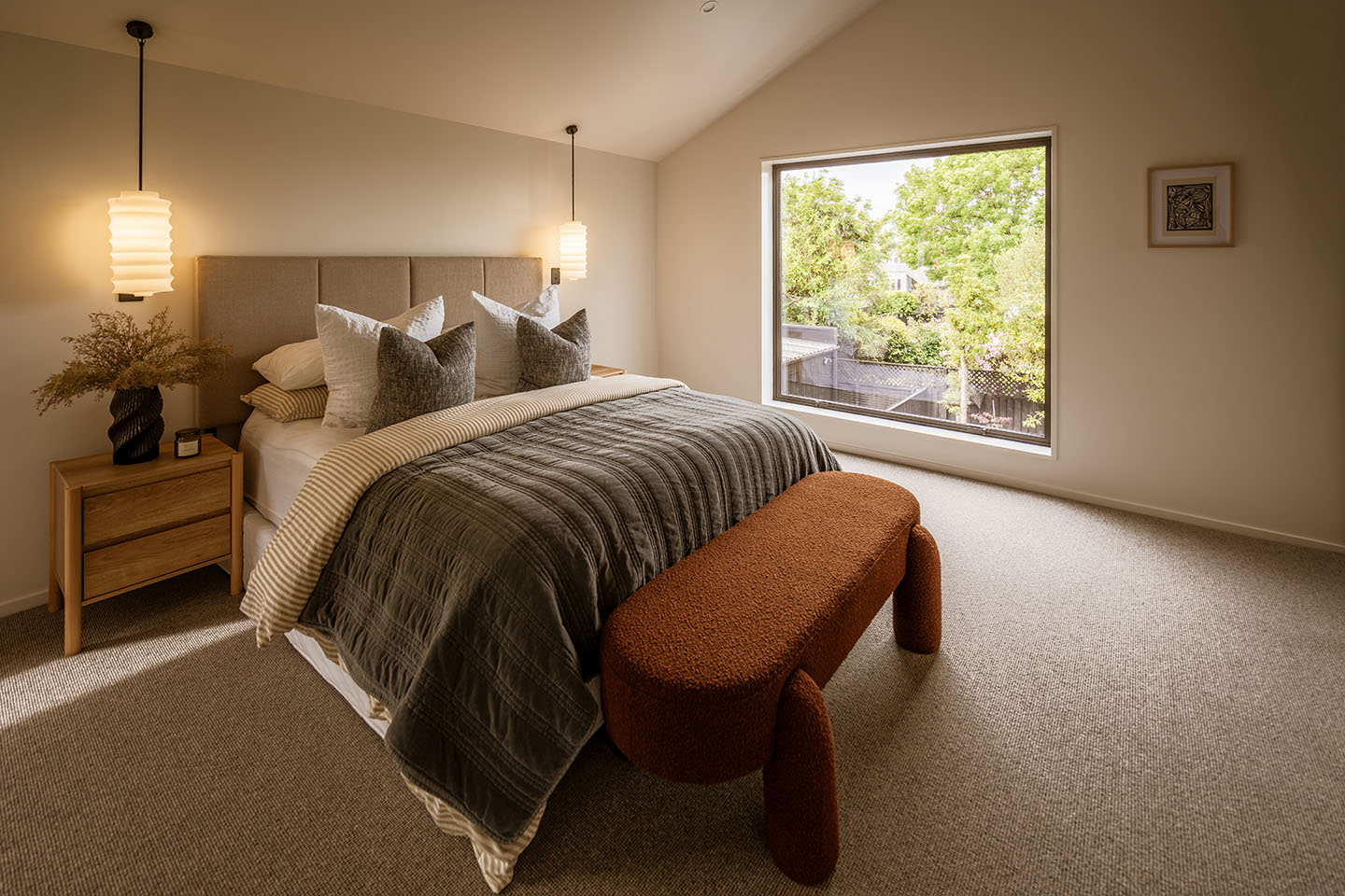 Bryndwr II bedroom with pendant lights beside the bed and a large picture window overlooking mature trees.