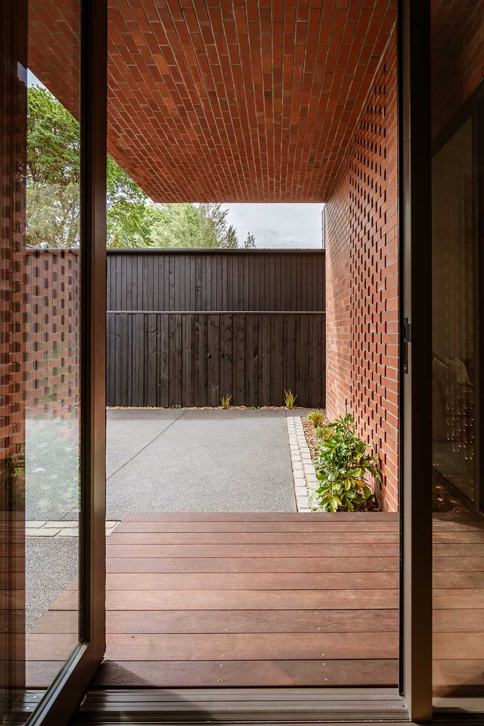 Bryndwr II entrance courtyard framed by brick walls and soffit, with perforated brick screening beside the doorway.