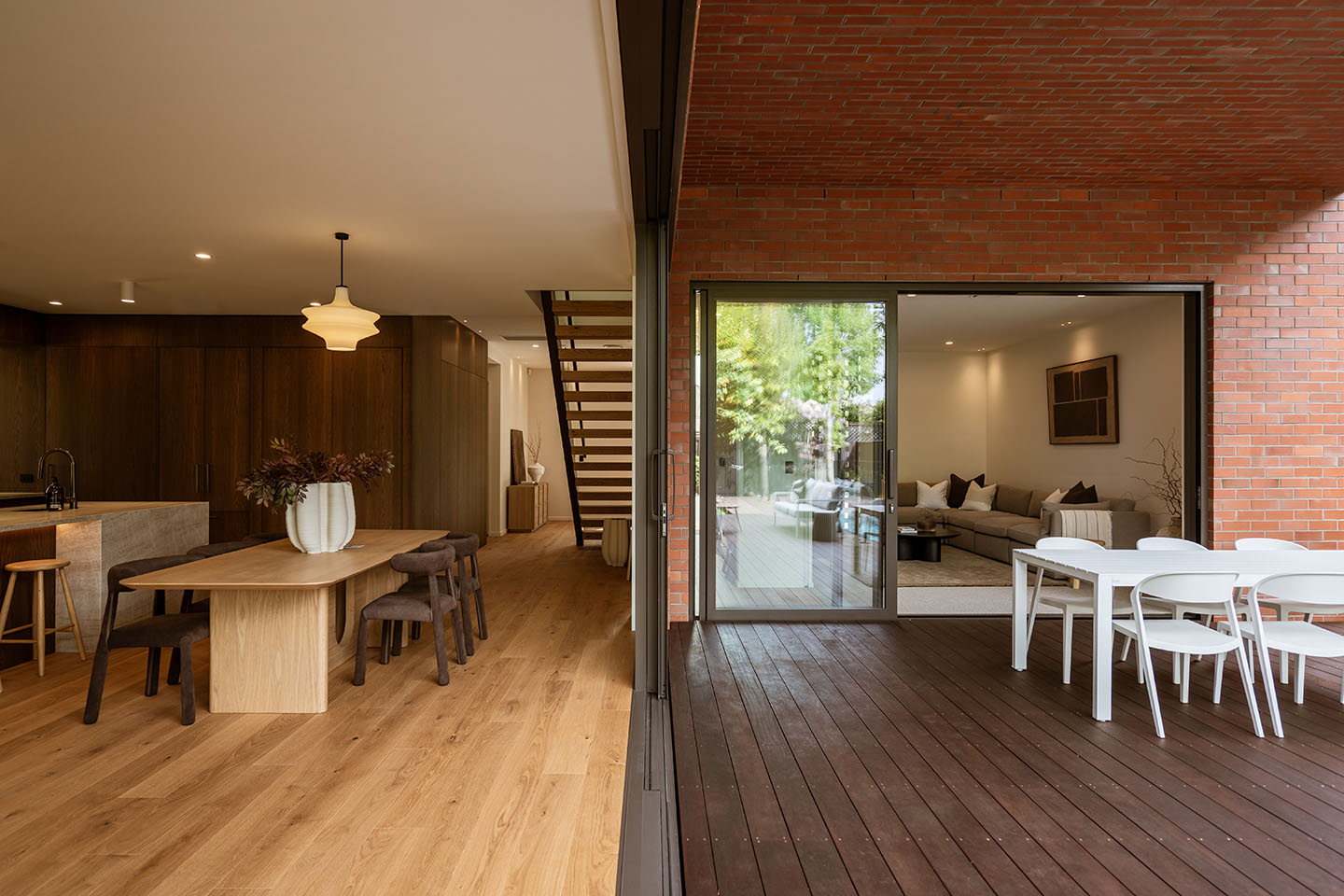 Bryndwr II dining area opening to a covered brick courtyard, with dark timber kitchen cabinetry and living spaces beyond.