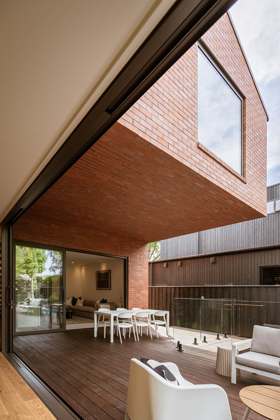 Bryndwr II covered courtyard beneath a cantilevered brick upper level, with outdoor dining beside the pool.