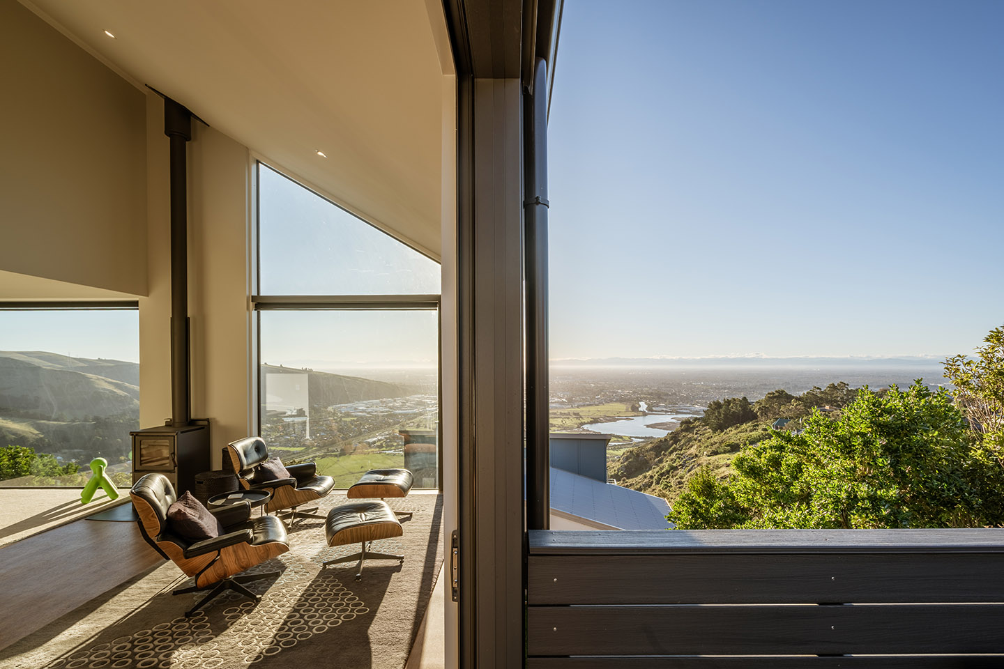 Major Hornbrook II living area beside full-height glazing, with lounge chairs overlooking the hillside, estuary and city below.