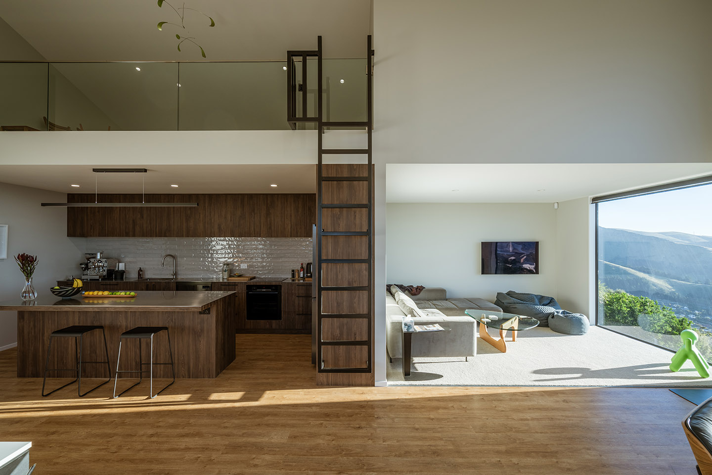 Major Hornbrook II open-plan kitchen and living area with timber cabinetry, a loft above and a steel ladder rising through the centre.