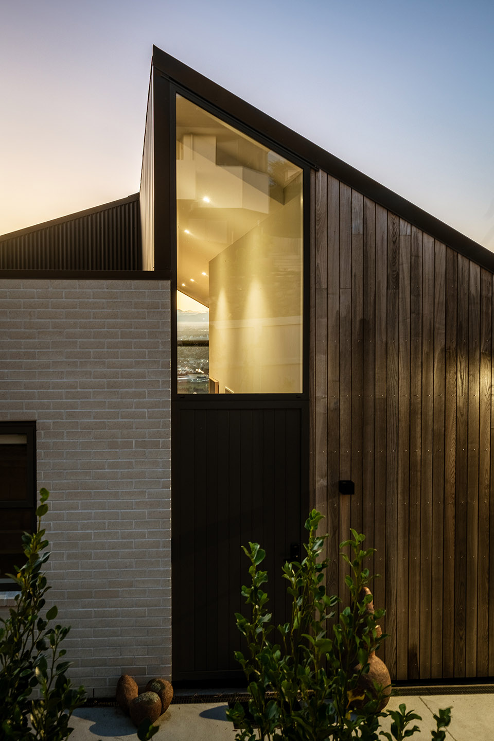 Major Hornbrook II exterior detail with timber cladding, pale brickwork and tall triangular glazing following the sloping roofline.