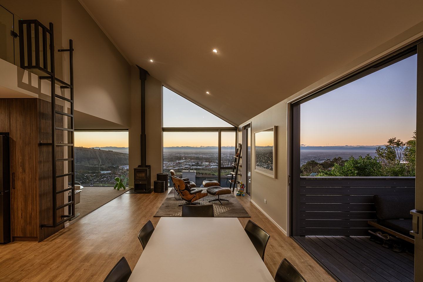 Major Hornbrook II dining and living space at dusk, opening to the deck with expansive views across Christchurch and the coast.