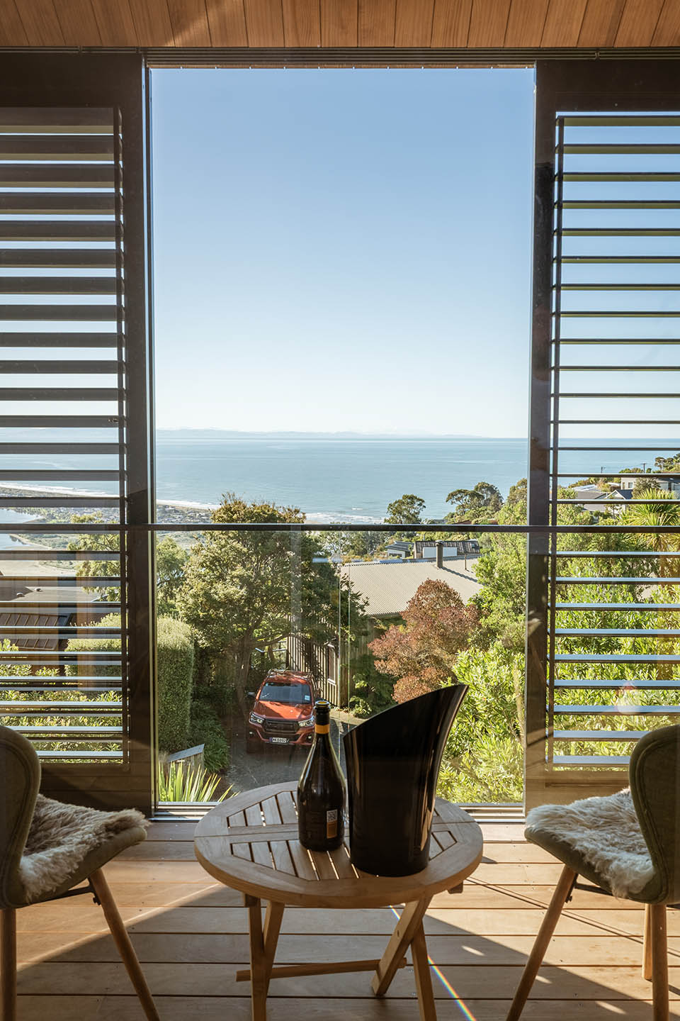 Revelation III deck with outdoor seating framed by vertical screens, overlooking the hillside and ocean beyond.