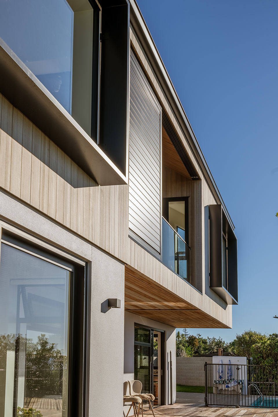 Revelation III exterior detail with vertical timber cladding, deep window surrounds and a glazed upper-level balcony above the deck.